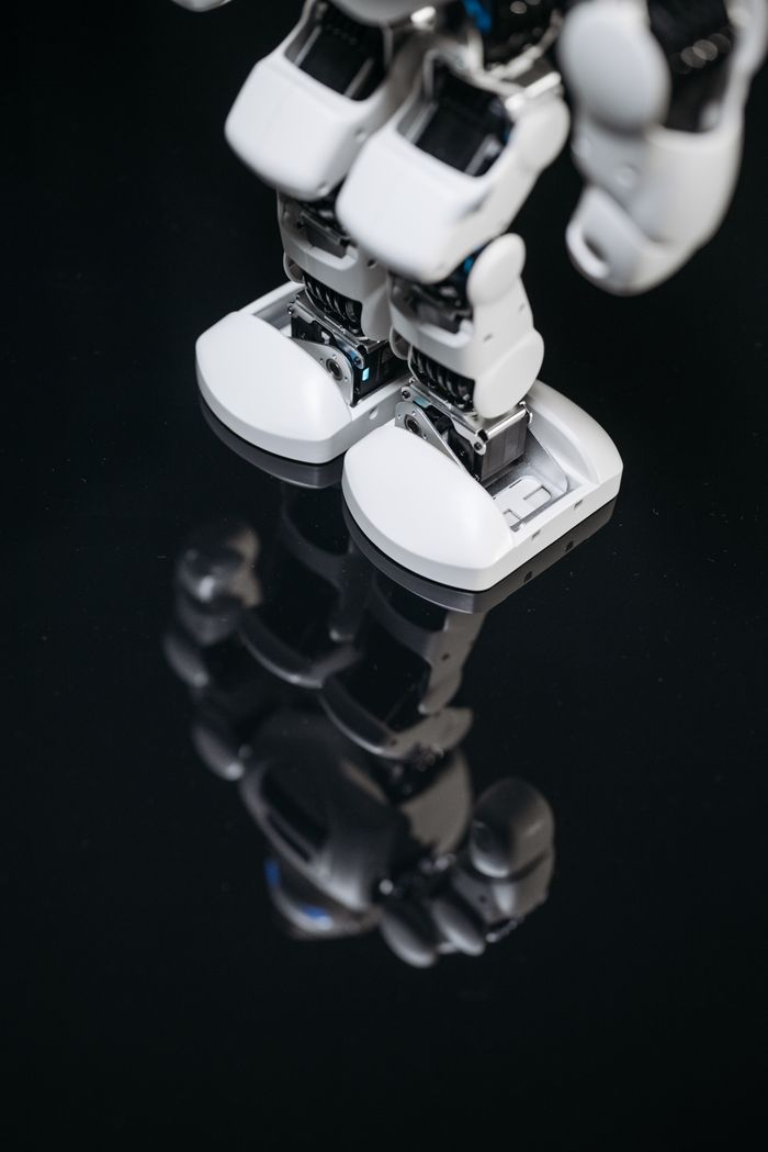 about-bg High-tech robot feet reflecting on a glossy surface, showcasing futuristic design.