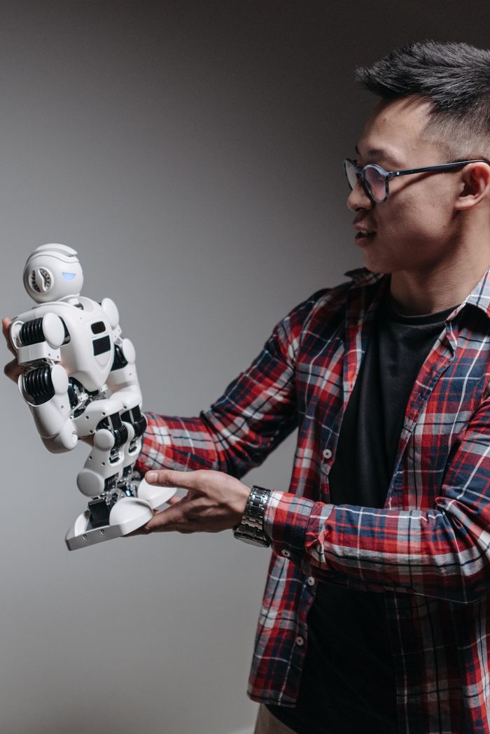 get-in-touch An adult man examines a humanoid robot against a gray background, exploring modern technology.